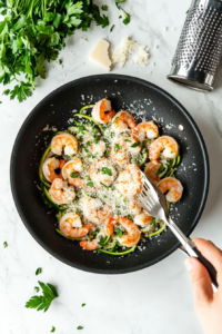 This image shows the dish being garnished with freshly grated parmesan cheese and chopped parsley for a finishing touch.