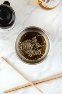 This image shows oil being heated in a small pan on a stovetop, creating the sizzling base needed to bring out the flavors of the garlic mixture for the creamy garlic noodles.