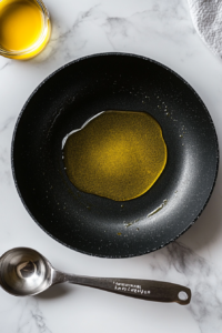 This image shows a hot pan with olive oil heating up, preparing to cook the shrimp.