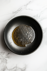 This image shows olive oil heating in a skillet, preparing to cook the shrimp and create the base for the honey mustard garlic sauce.