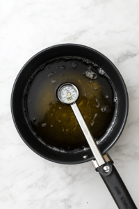 this image shows A saucepan filled with 2 inches of vegetable oil, heated to 350°F, ready for frying the coated oyster mushrooms.