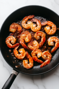 This image shows the skillet heat being turned up to prepare for adding the shrimp, ensuring a quick and even cook.