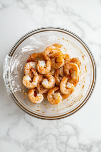 This image shows a jar of pickled shrimp placed in the refrigerator, allowing the shrimp to marinate and develop their tangy flavor.