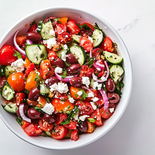 This image shows a Keto Greek Cucumber Salad in a white bowl, topped with a salad dressing made by whisking together olive oil, red wine vinegar, lemon juice, minced garlic, oregano, salt, and black pepper, enhancing the freshness of the salad.