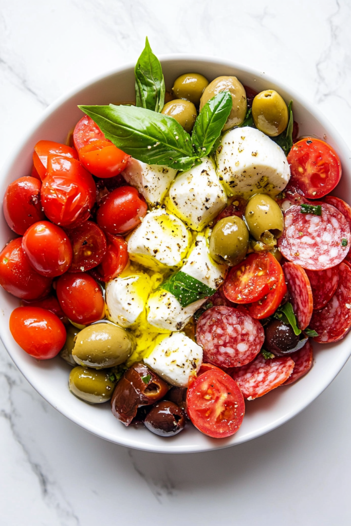 this image shows vibrant keto antipasto salad drizzled with freshly prepared lemon vinaigrette, served in a white bowl, perfect for summer dining.