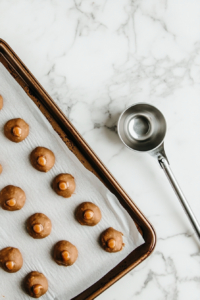 A baking sheet lined with parchment paper, ready to hold scoops of salted caramel cookie dough for baking.