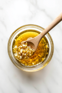 This image shows Dijon mustard, honey, and minced garlic being combined in a bowl to create the sauce for the honey mustard garlic shrimp, highlighting the ingredients before they are blended together.