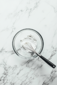 this image shows A small bowl with cornstarch being whisked into plant-based milk, preparing a smooth and creamy mixture for the vegan mushroom stroganoff sauce.