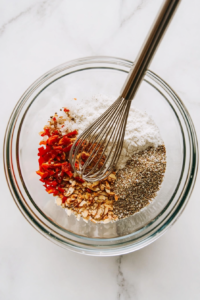 this image shows A bowl containing almond flour, seasonings, and spices being mixed together to create the breading mixture for keto coconut shrimp.