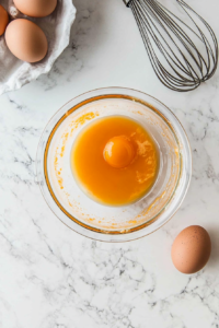 This image shows egg replacer being whisked with hot sauce in a bowl to form a spicy batter for dredging tofu nuggets.