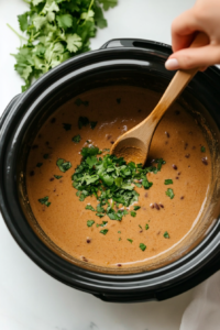 This image shows freshly chopped cilantro being stirred into the Crockpot White Chicken Chili, adding a burst of fresh flavor and vibrant color to the dish.