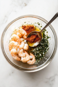 This image shows a bowl of melted butter being mixed with minced garlic and seasonings, creating a flavorful marinade for the shrimp.