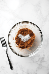 This image shows a bowl filled with a seasoning blend of paprika, brown sugar, salt, and pepper, mixed together to coat the pork for slow cooking.