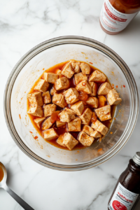 This image shows a bowl of plant-based milk being combined with vinegar, creating vegan buttermilk for coating the tofu.