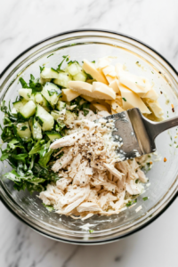 This image shows the shredded chicken being thoroughly mixed with the seasoned mayo and sour cream until well combined and evenly coated.