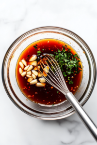 This image shows a glass bowl filled with soy sauce, ketchup, honey, minced garlic, and fresh basil leaves being mixed together to create a flavorful sauce for crockpot chicken thighs.