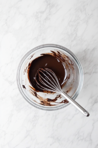 This image shows a bowl filled with crust ingredients being carefully mixed to form a consistent and crumbly texture for the vegan chocolate tart base.