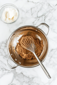 This image shows a saucepan on the stovetop, where coconut milk, vegan sugar, cornstarch, and soy lecithin are being whisked together to create the creamy filling base.