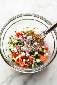 This image shows the salad dressing ingredients being mixed thoroughly in a bowl, ready to be poured over the salad for added flavor.