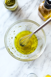 This image shows freshly prepared pesto in a small bowl, made from basil, olive oil, and garlic, to enhance the flavor of the Caprese salad skewers.