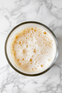 This image shows water, yeast, and salt being whisked together in a large mixing bowl to create the base for the no-knead Dutch oven bread dough.