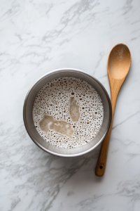 This image shows yeast, sugar, and warm water being combined in a bowl to activate the yeast for the Focaccia bread.