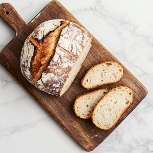 This image shows a loaf of no yeast bread on a wooden chopping board with a few slices placed neatly on the side. The bread has a golden crust on the outside and a soft, fluffy texture on the inside.