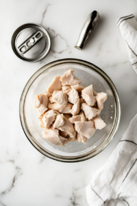 This image shows a can of chicken being opened and drained to prepare the base for the protein-packed carnivore chicken salad.