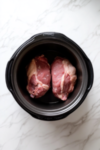 this image shows This image shows a pork tenderloin being carefully placed into a slow cooker, ready to be slow-cooked to tender perfection.