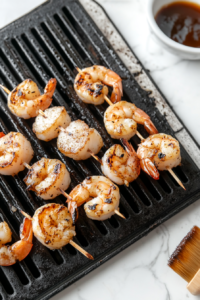 This image shows skewers of shrimp and scallops being placed on a hot grill, starting the cooking process with a delightful sizzle.