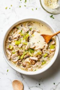 This image shows the egg and cream mixture being poured evenly over the turkey and vegetable filling in the casserole dish.