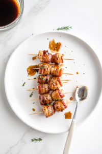 This image shows a final drizzle of barbecue sauce being poured over cooked bacon-wrapped shrimp to enhance the flavor and presentation.