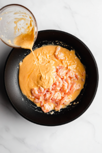 This image shows the honey mustard garlic sauce being poured over the cooked shrimp in the skillet, ready to infuse the shrimp with its rich flavor.