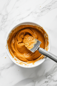 This image shows a smooth, spiced pumpkin filling being poured into the prepared almond butter crust, ready for baking into a vegan and gluten-free pumpkin pie.