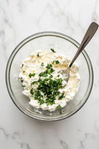 This image shows a bowl with ricotta cheese, eggs, and seasonings being mixed together to create a rich and creamy filling for the lasagna layers.