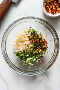 This image shows minced garlic and finely chopped spring onions placed in a bowl, being prepared as the base for the garlic mixture used in the creamy garlic noodles recipe.