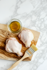 This image shows raw chicken breasts being trimmed and prepared on a cutting board, ensuring they are ready to absorb the marinade and cook evenly.