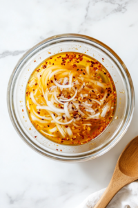 This image shows a clear jar filled with pickling liquid, infused with herbs and spices, ready to be refrigerated to enhance its flavors.