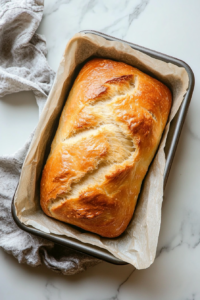 This image shows the baked loaf of no yeast bread being carefully taken out of the oven, with a golden crust visible on top.