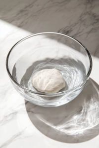 This image shows the dough submerged in a bowl of water, resting to allow the gluten to relax for the next step.