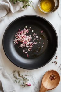 This image shows shallots being sautéed in a pan, releasing aromatic flavors to form the base of the Keto Eggplant Lasagna filling.