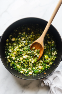 this image shows Garlic and Brussels sprouts being sautéed in olive oil in a large pot, releasing their aromas and flavors to create a savory base for the creamy pasta.