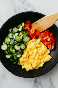 This image shows eggs being scrambled in a skillet, creating fluffy and flavorful pieces that will be mixed into the shrimp fried rice.