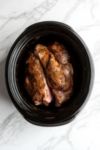 This image shows the seasoned pork lying in the crockpot, ready to slow cook to tender perfection.