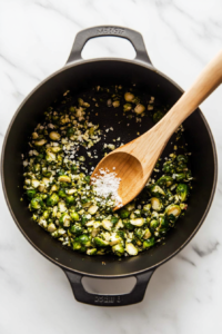 this image shows Salt, pepper, and fresh lemon juice being added to sautéed garlic and Brussels sprouts, enhancing the flavors for the vegan creamy garlic pasta.