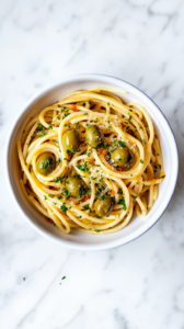 this image shows A beautifully plated Vegan Green Olive Pasta Sauce, topped with shredded cheese, chopped cilantro, and sliced green olives, ready to be enjoyed as a delightful meal.