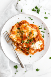 This image shows a portion of Crockpot Lasagna being served from the crockpot, showcasing the melted cheese and perfectly cooked layers.