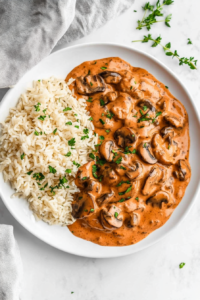 this image shows beautifully plated serving of creamy vegan mushroom stroganoff, accompanied by fluffy rice and garnished with fresh cilantro, ready to be enjoyed as a comforting, hearty meal.