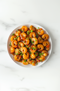 This image shows honey mustard garlic shrimp served on a plate, garnished with chopped spring onions, ready to be enjoyed as a flavorful and satisfying meal.