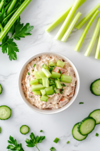 This image shows a serving of keto deviled ham salad in a white bowl, accompanied by fresh vegetable sticks, perfect for dipping or spreading.